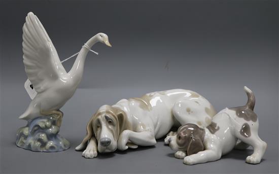 A Lladro figure of a recumbent bloodhound, another of a playful puppy and a Nao figure of a swan